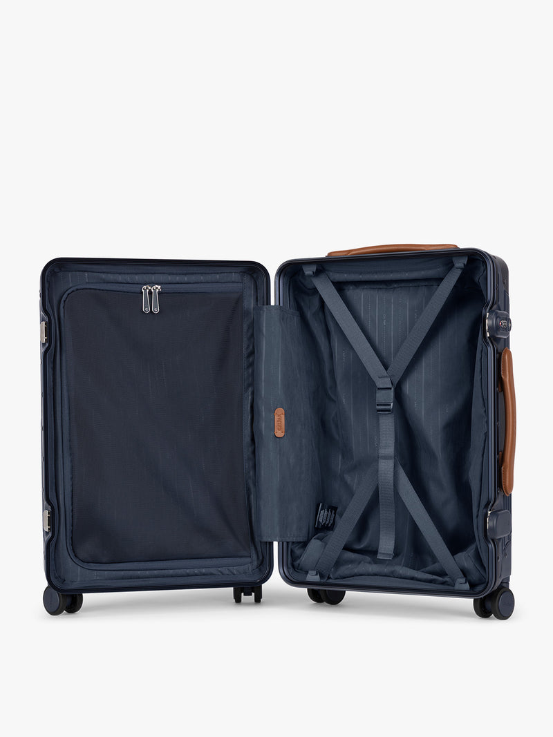 Opened CALPAK Vault Luggage blue Navy hard-shell spinner suitcase with a ribbed vertical design, shown from the front against a clean white background