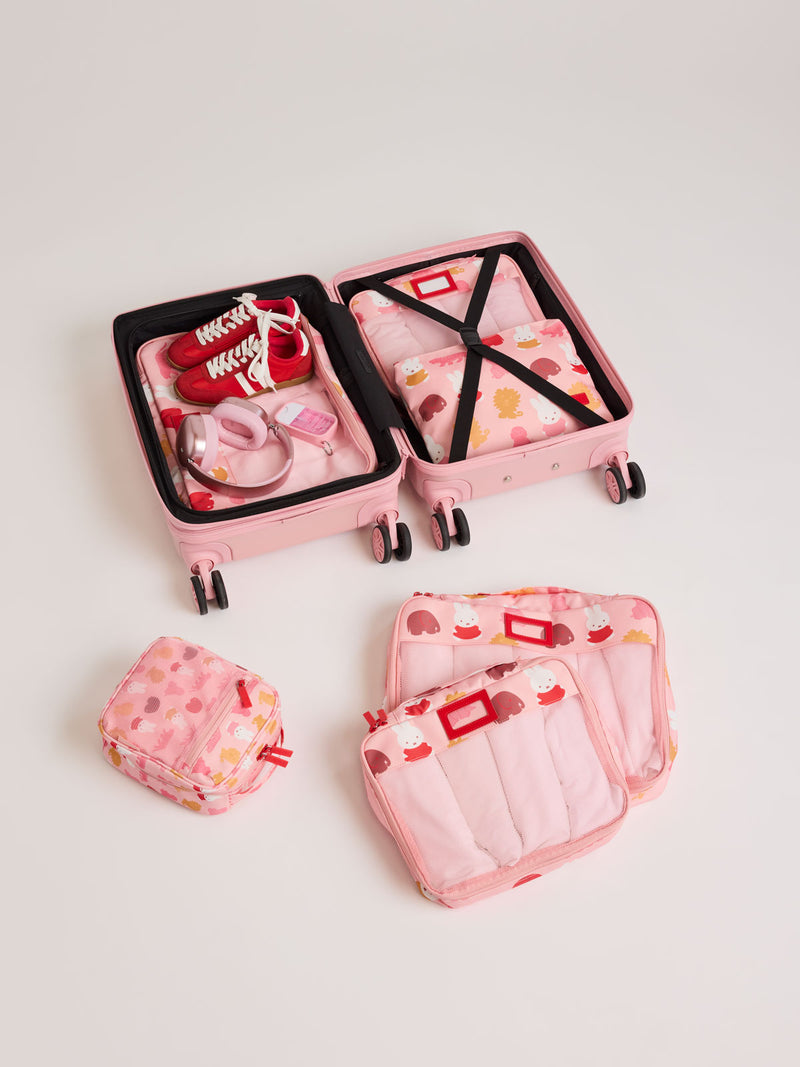 Set of CALPAK Packing Cubes in colorful pink pouches with Miffy and animal pattern  packed in a suitcase on a white background
