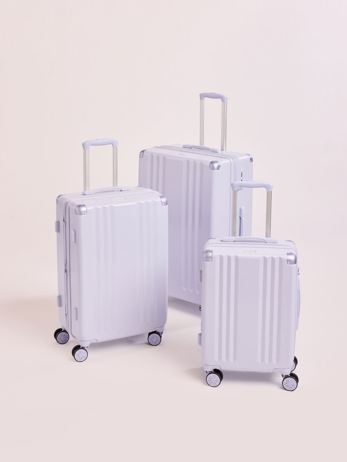 CALPAK Ambeur three piece luggage set in carry on, medium, and large sizes in light purple lavender with handles and spinner wheels on a white background; LAM3000-SEA-GLASS