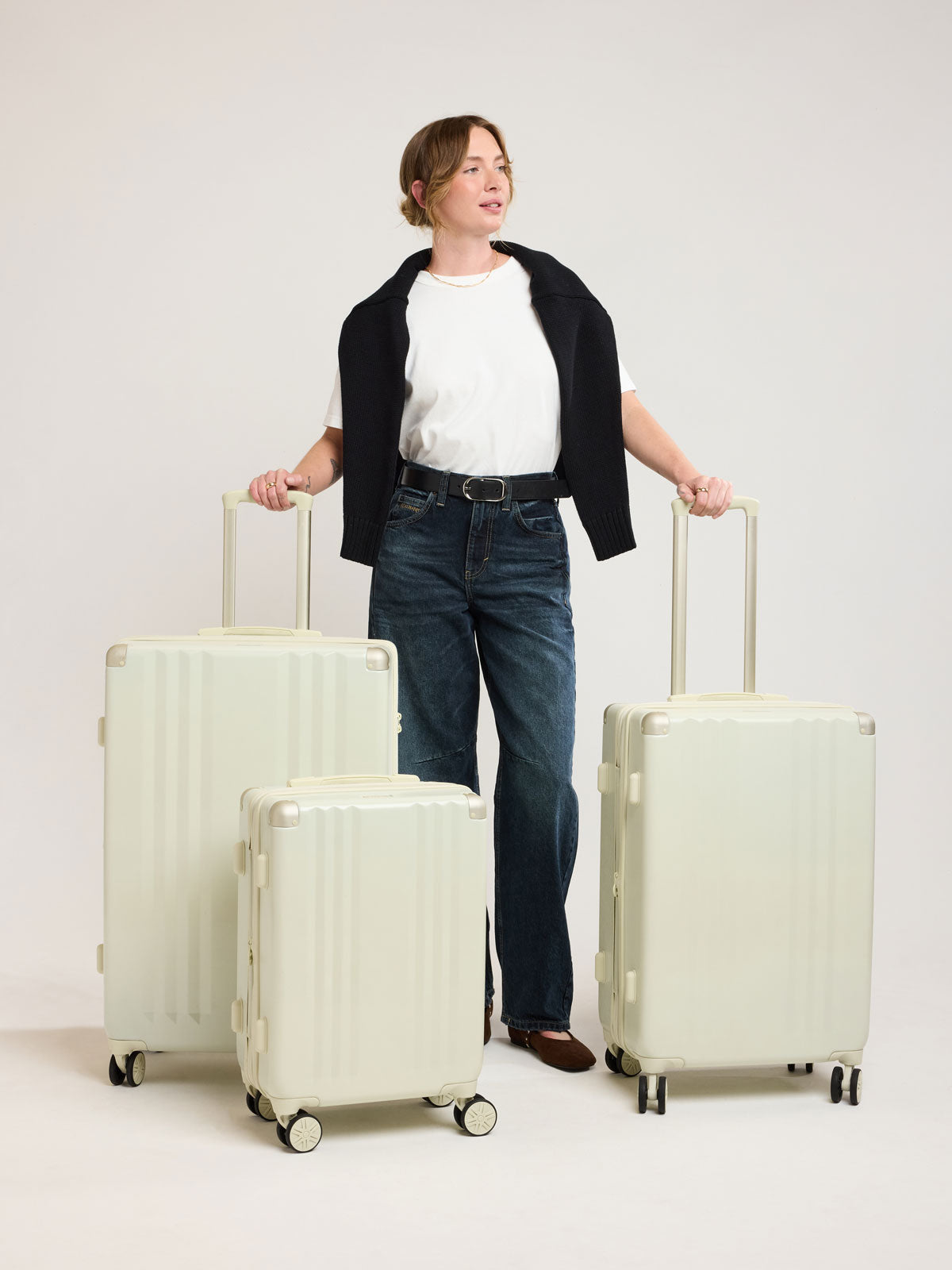 Woman wirh CALPAK Ambeur 3 piece Luggage Set in light green Celadon with sizes of Carry On, Medium, and Large; LAM3000-CELADON
