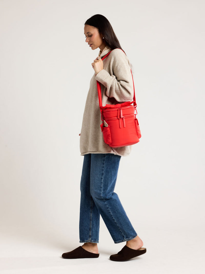 Woman wearing the CALPAK Insulated Baby Bottle Bag in red Tomato