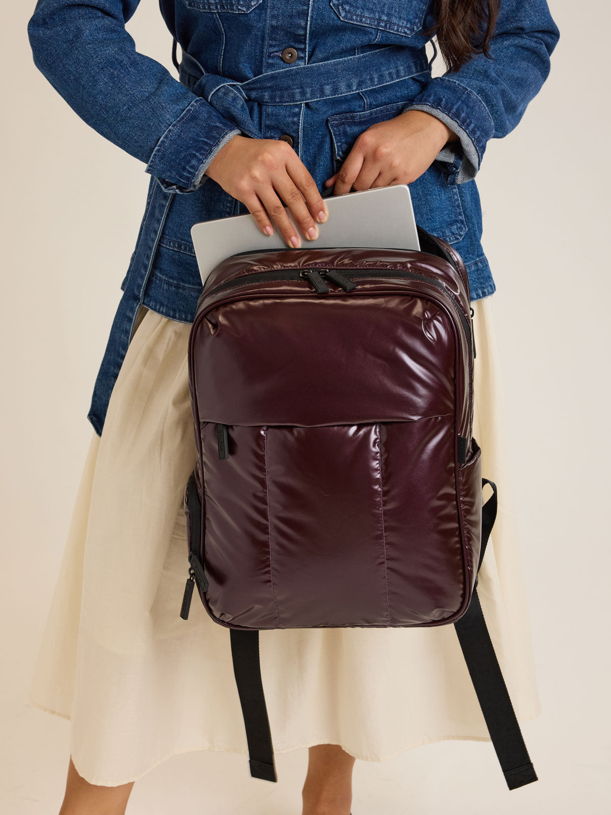 Model holding CALPAK Luka Backpack in maroon Dark Cherry ; BPL2001-GLAZED-DARK-CHERRY