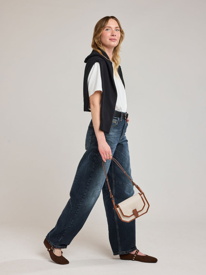 Woman holding CALPAK Colette Canvas Crossbody Wallet Bag in Natural Brown with beige canvas material and brown finishing