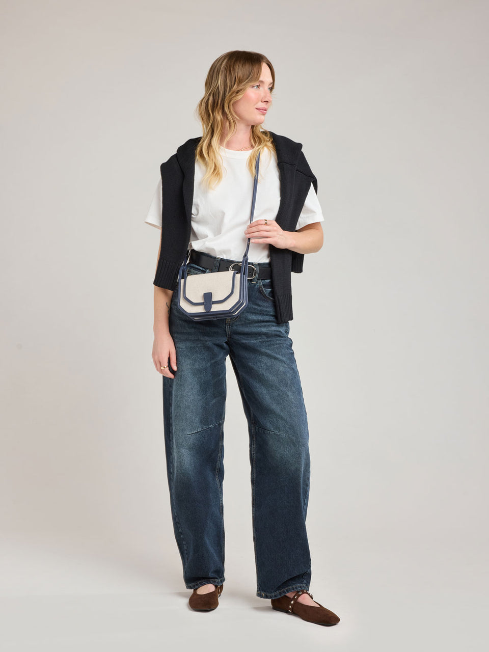 Woman wearing CALPAK Colette Canvas Crossbody Wallet Bag in Natural Brown with beige canvas material and blue finishing; CLWC2601-NATURAL-NAVY