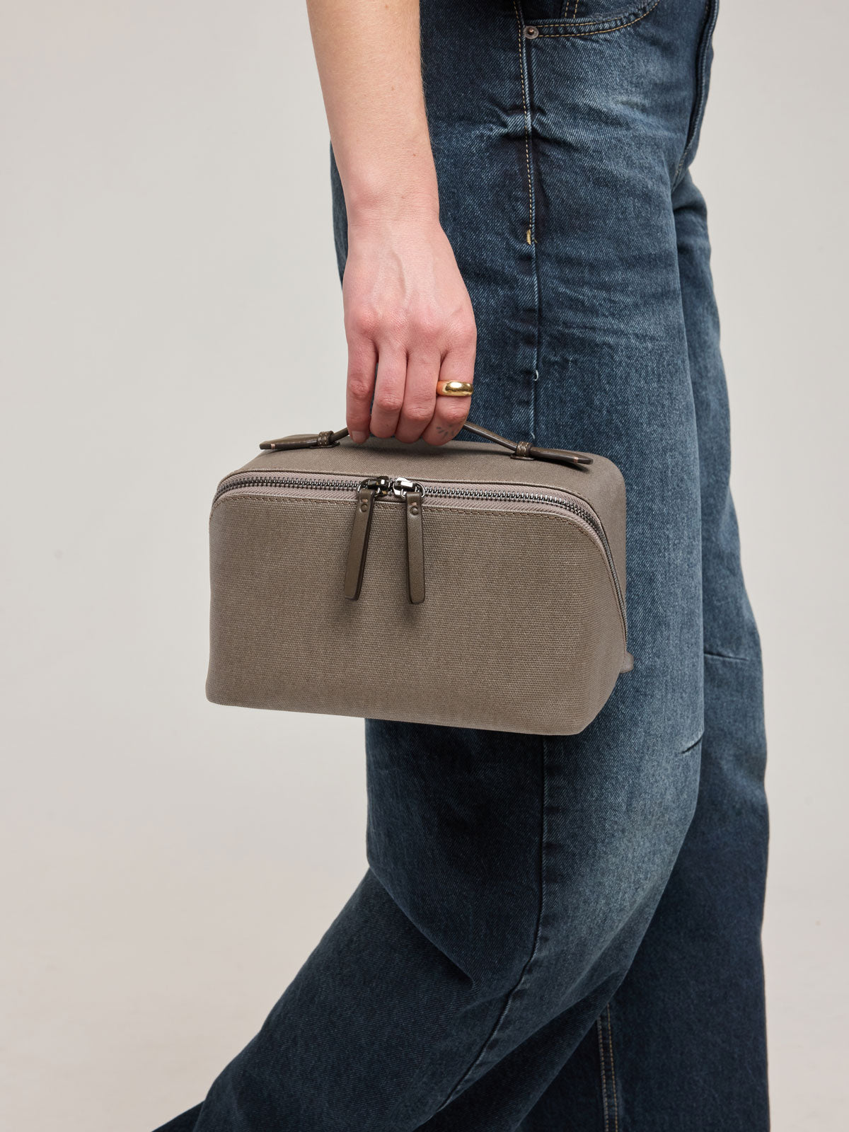 Woman wearing CALPAK Colette Lay-Flat Canvas Toiletry Bag in brown Mushroom canvas material ; CLTB2601-MUSHROOM