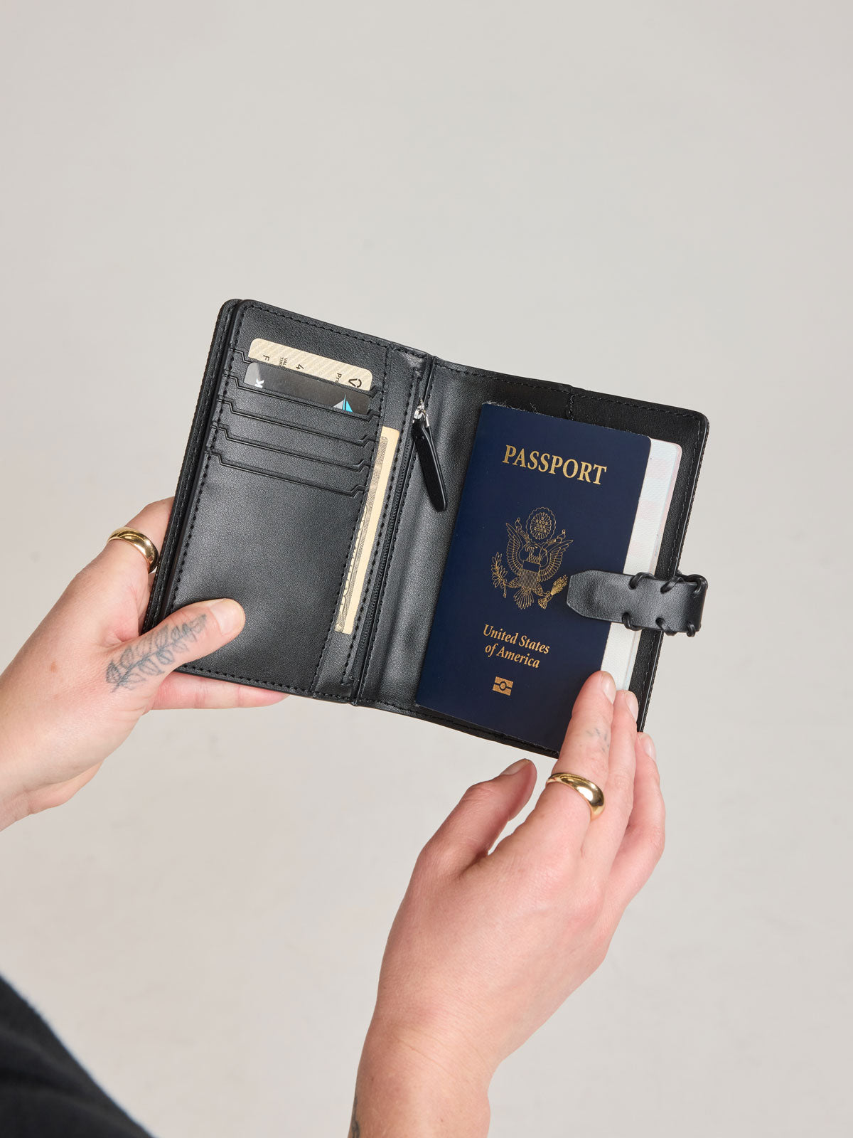 Model holding open CALPAK Colette Multi Passport Wallet in Black canvas material; CLPW2601-BLACK