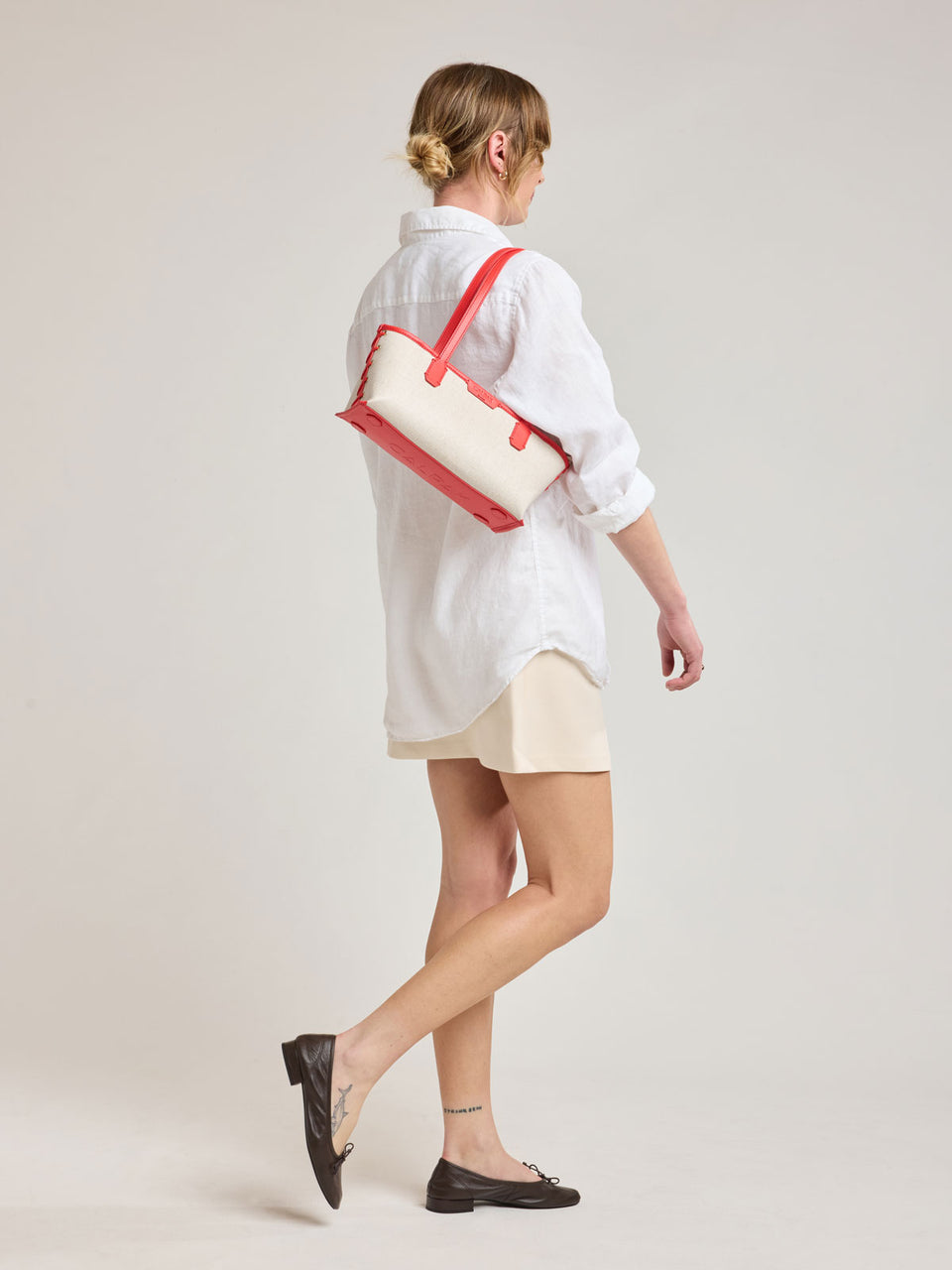 Woman wearing CALPAK Colette Canvas Shoulder Tote in beige canvas material  and red finishing; CLST2601-NATURAL-TOMATO