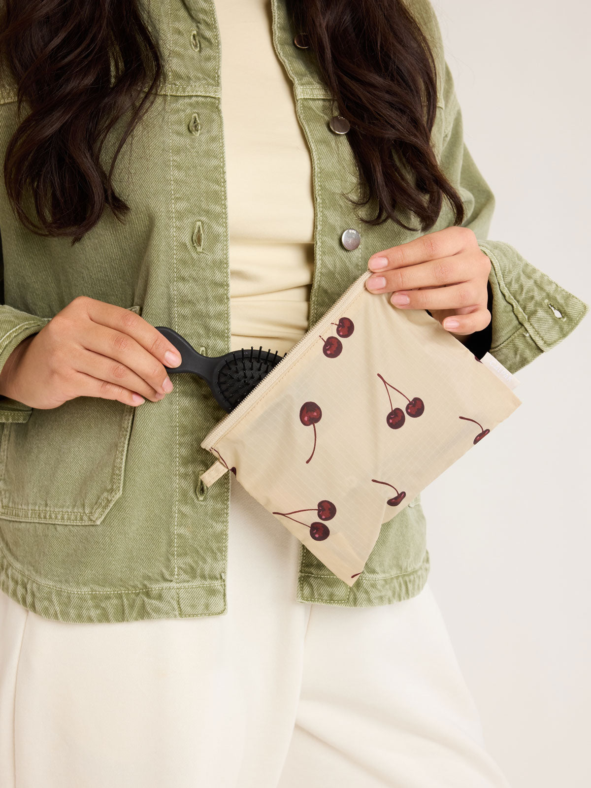 Model holding CALPAK  Compakt Zippered Pouch in beige with cherry pattern; KZB2001-OATMEAL-CHERRY