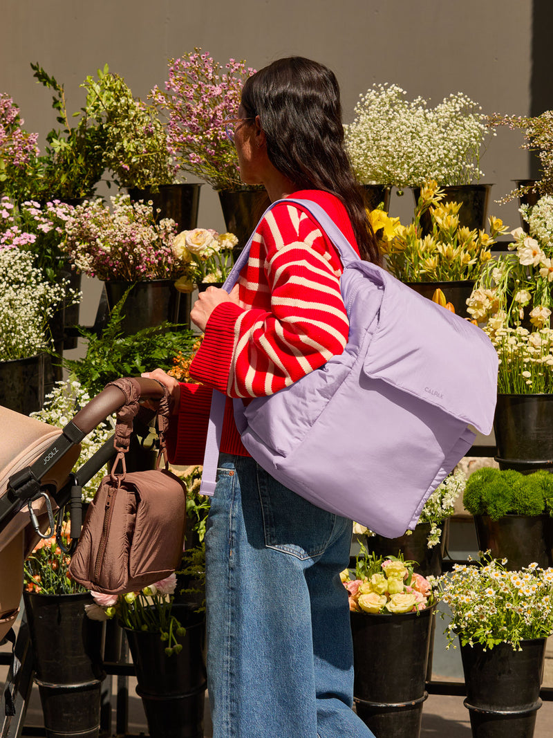 Model wearing the CALPAK Diaper Backpack in lavender purple Orchid