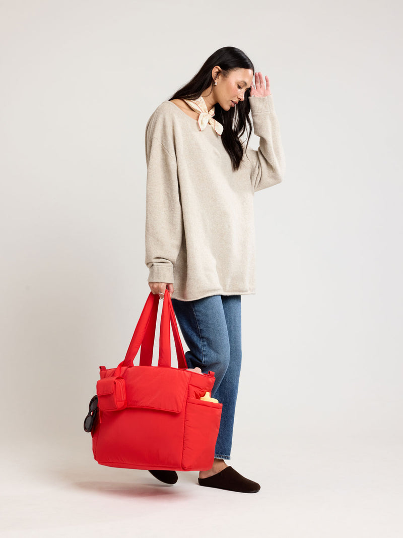 Woman holding CALPAK Diaper Tote bag in red Tomato