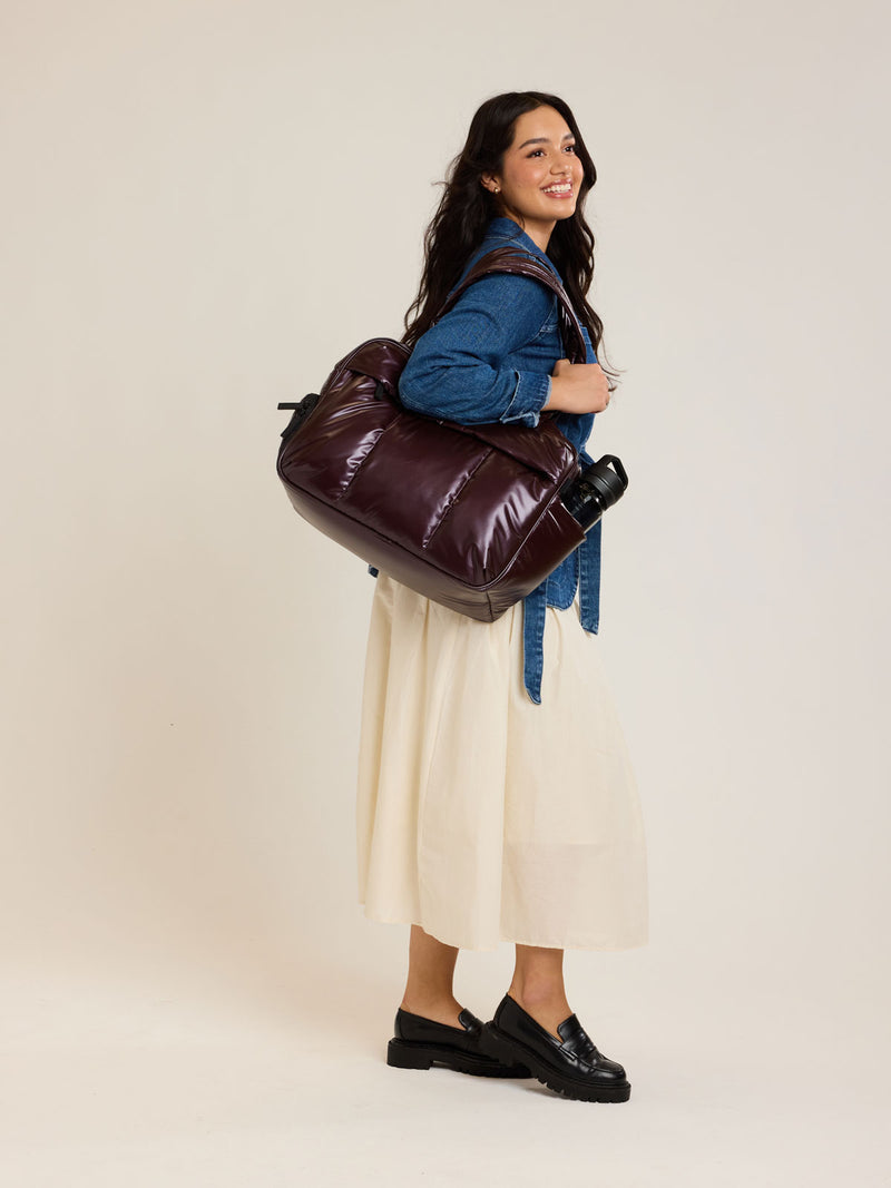 Model with CALPAK Dark Cherry red Luka Duffel front view on a white background
