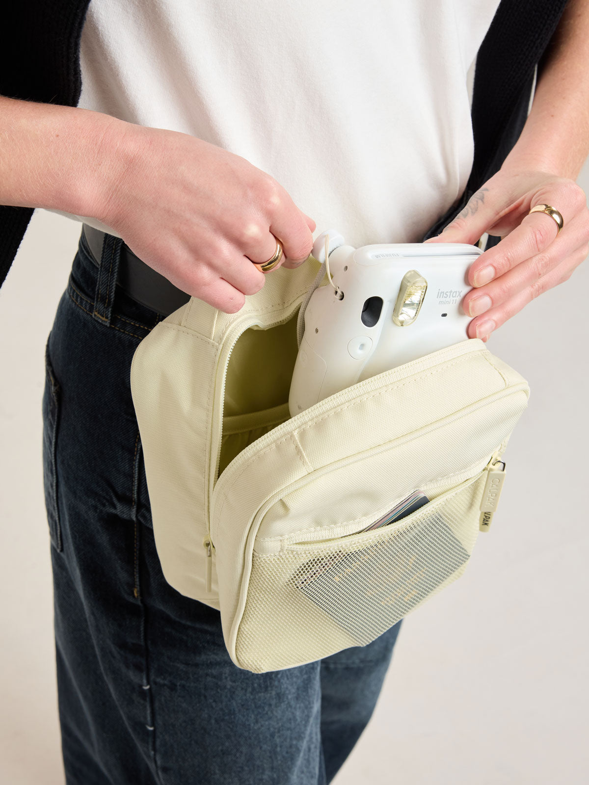 Person putting a polaroid camera into CALPAK Everything Cube in light green Celadon; ACE2401-CELADON