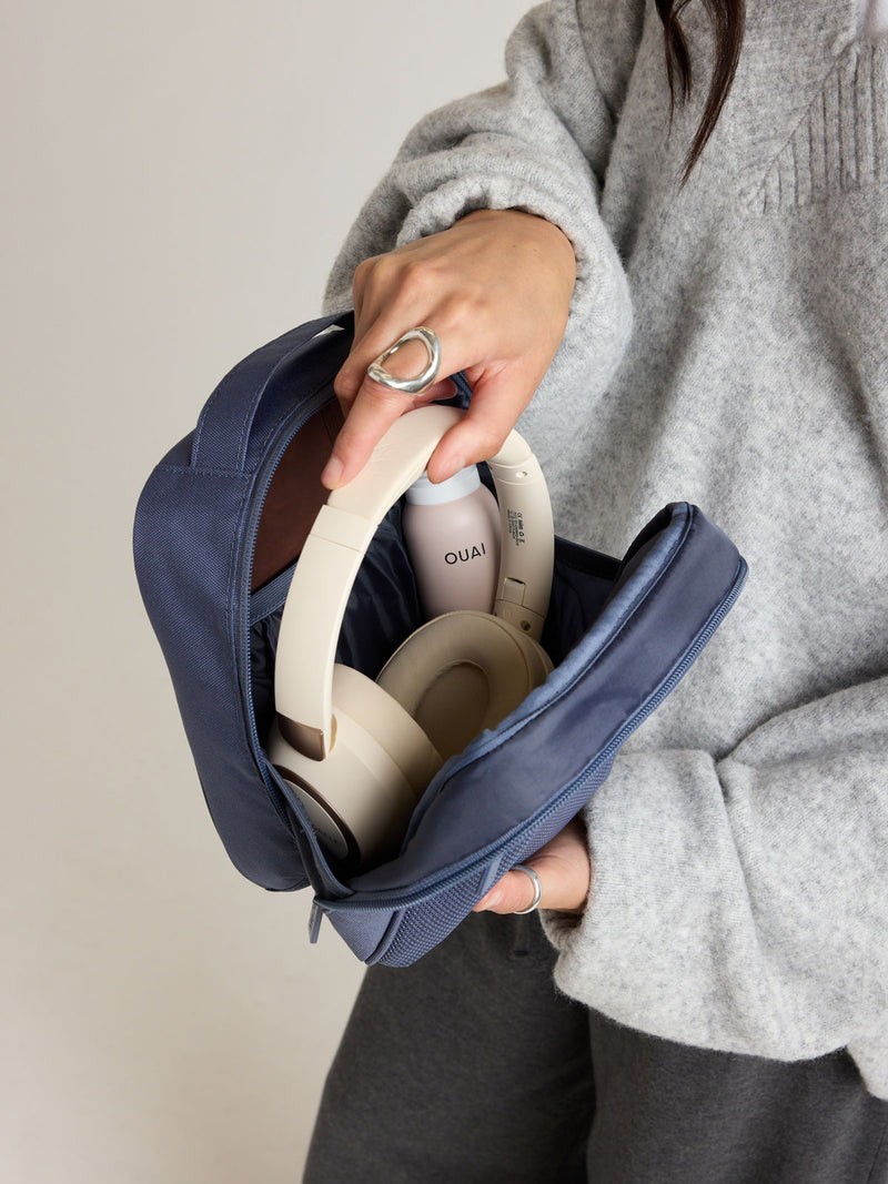 Person adding headphones into the CALPAK Everything Cube in dark blue Indigo