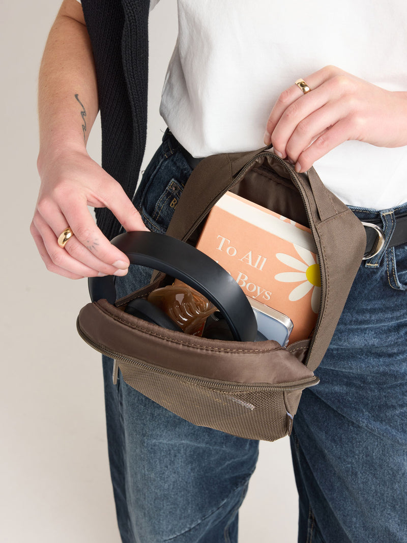 Person putting headphones into CALPAK Everything Cube in brown Mushroom