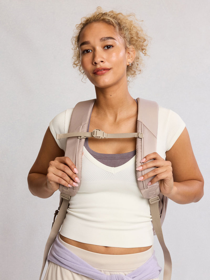 Front view of model wearing CALPAK Fit Gym Backpack in beige Greige front view with white background