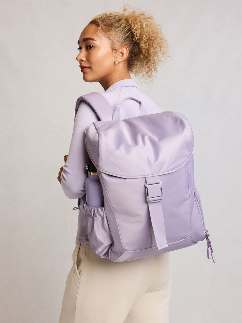 Model wearing CALPAK Fit Gym Backpack in light purple Iris front view with white background