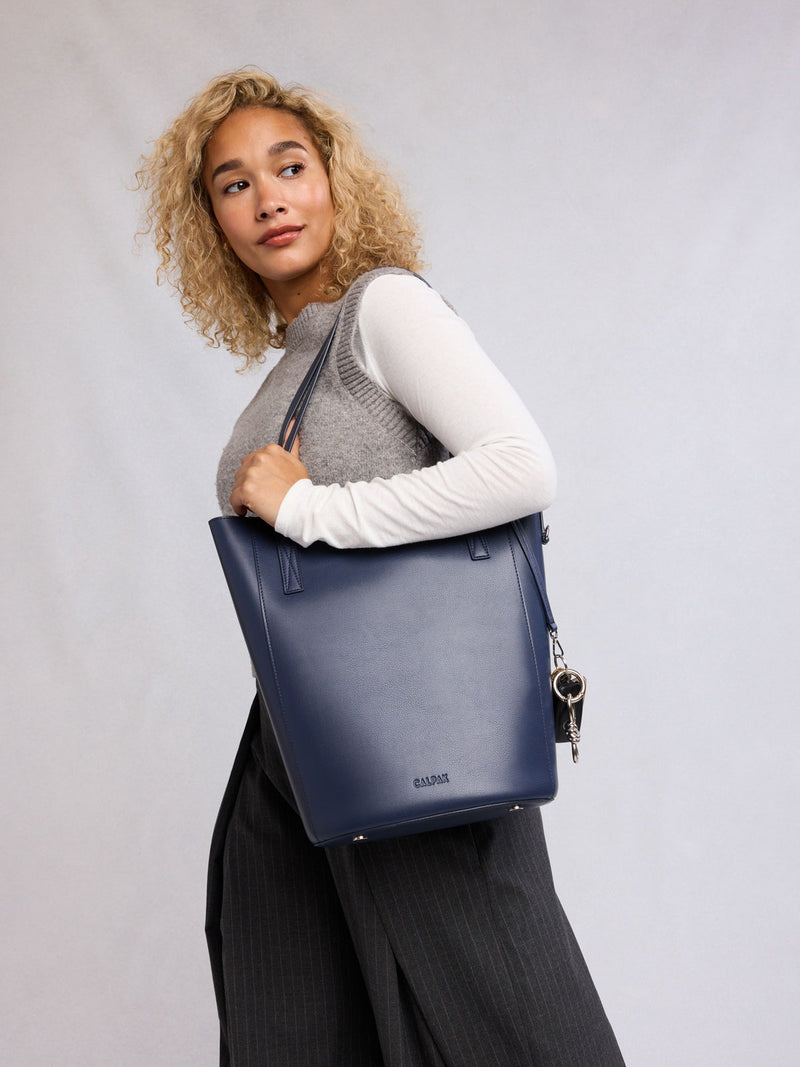 Woman holding the CALPAK Haven 14" Haven Laptop Tote in dark blue Navy