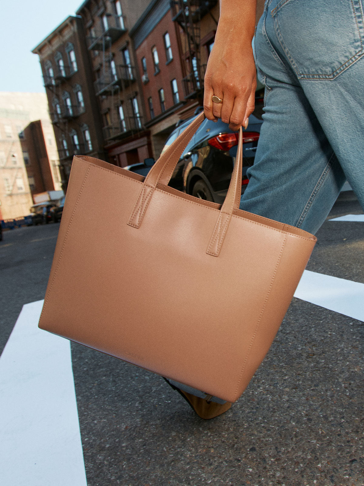 Model holding the straps of the CALPAK Haven 15 inch Laptop Tote in beige Taupe; ATS2501-TAUPE