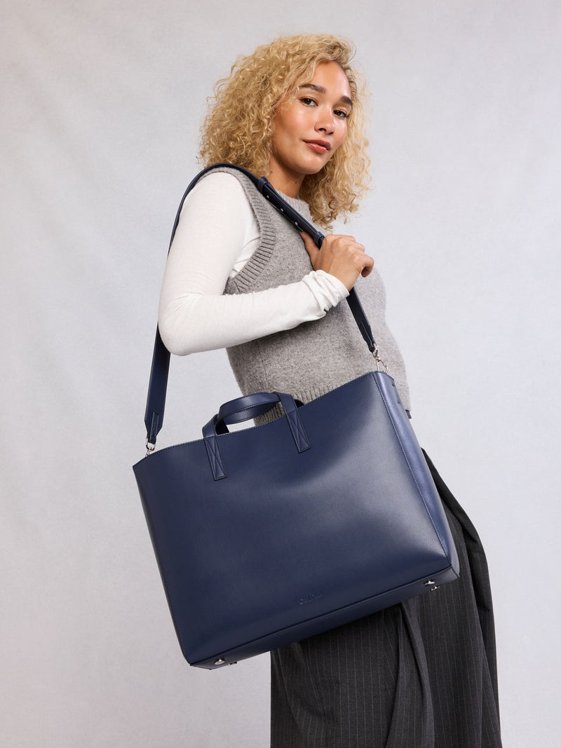 Model wearing the CALPAK Haven 16" Laptop Tote in dark blue Navy