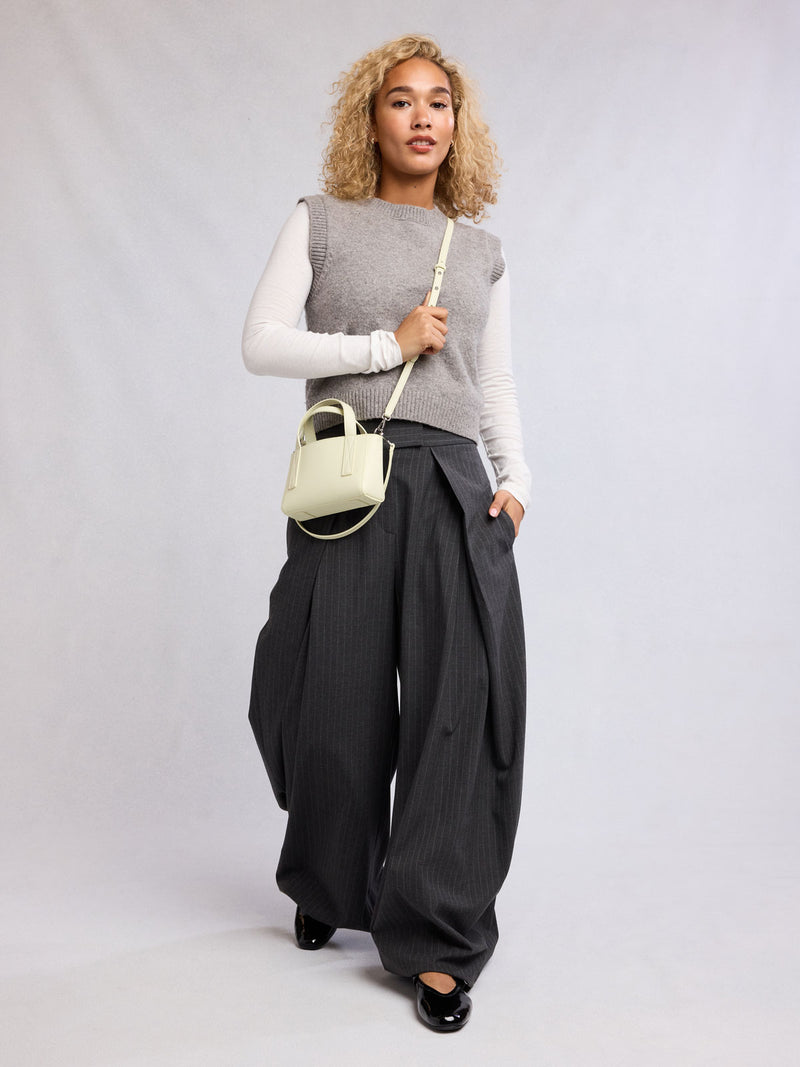 Woman wearing the CALPAK Haven Mini Crossbody Bag in light green Celadon