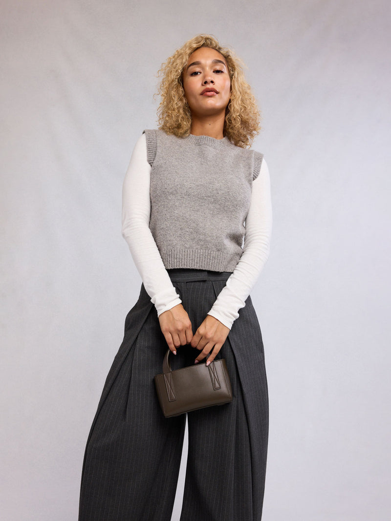 Model holdng CALPAK Haven Mini Crossbody Bag in dark brown Mushroom