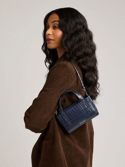A CALPAK Haven Mini Crossbody Bag in Navy blue crocodile-embossed with top handles on a plain white background; AMC2502-NAVY-FAUX-CROC view 2