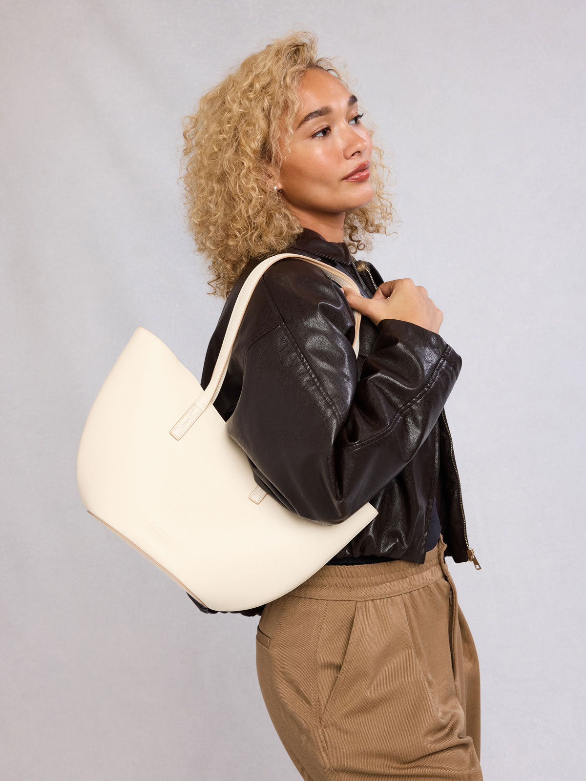 Woman holding CALPAK Haven Tulip Tote in beige Buttercream; AHP2601-BUTTERCREAM