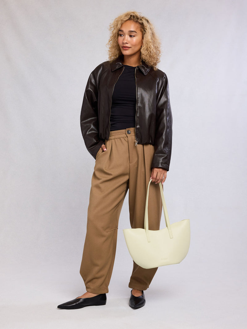 Woman with CALPAK Haven Tulip Tote in beige Buttercream