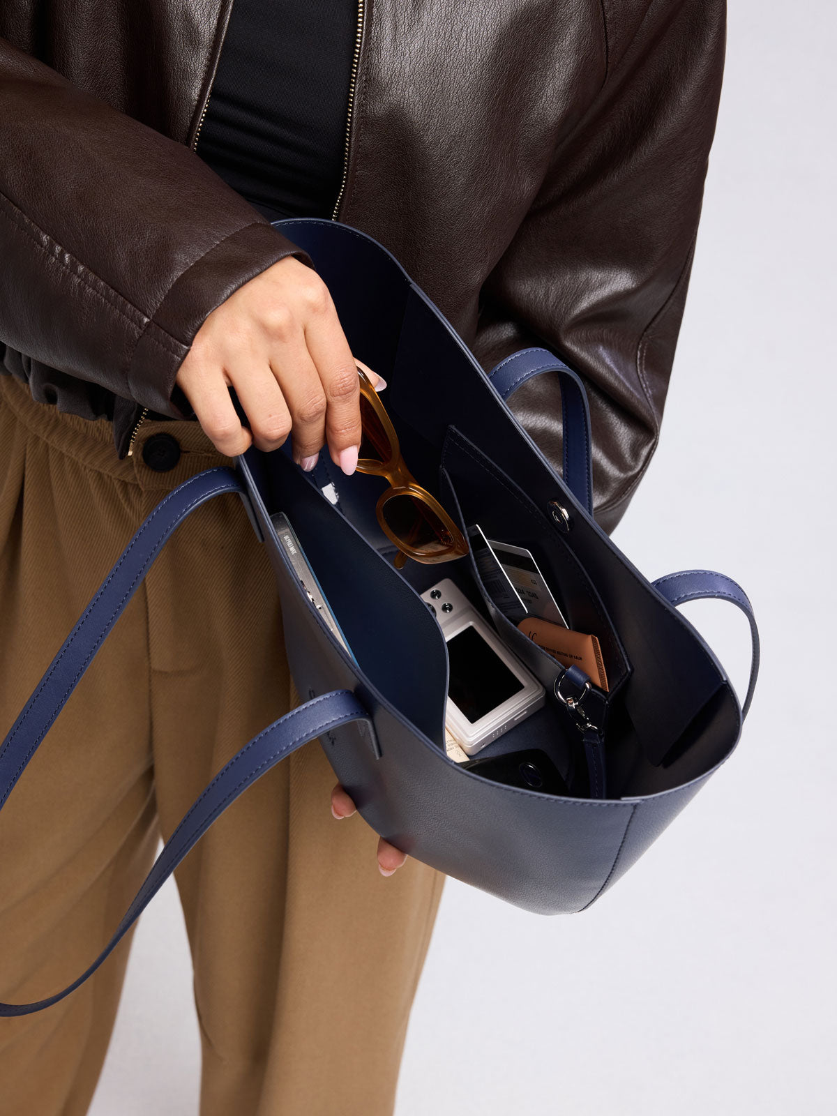 Person adding images into CALPAK Haven Tulip Tote in dark blue; AHP2601-NAVY