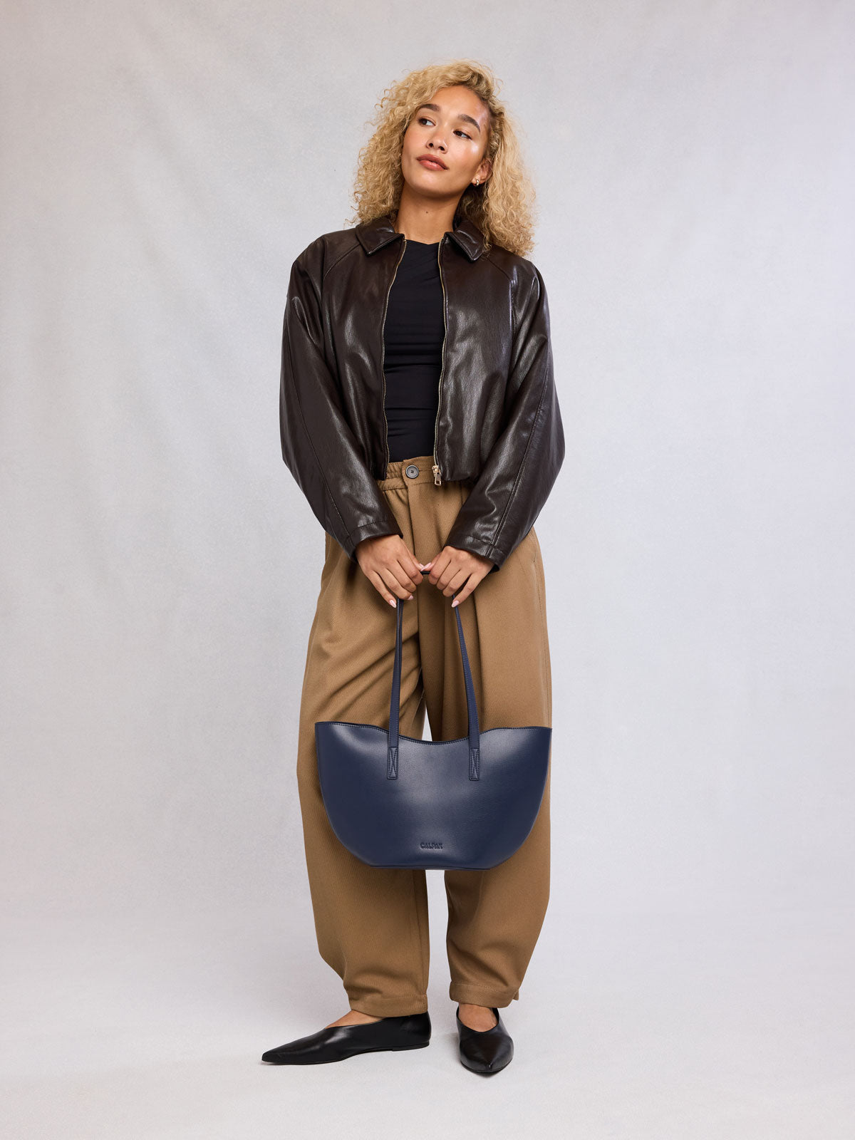 Woman holding CALPAK Haven Tulip Tote in dark blue; AHP2601-NAVY