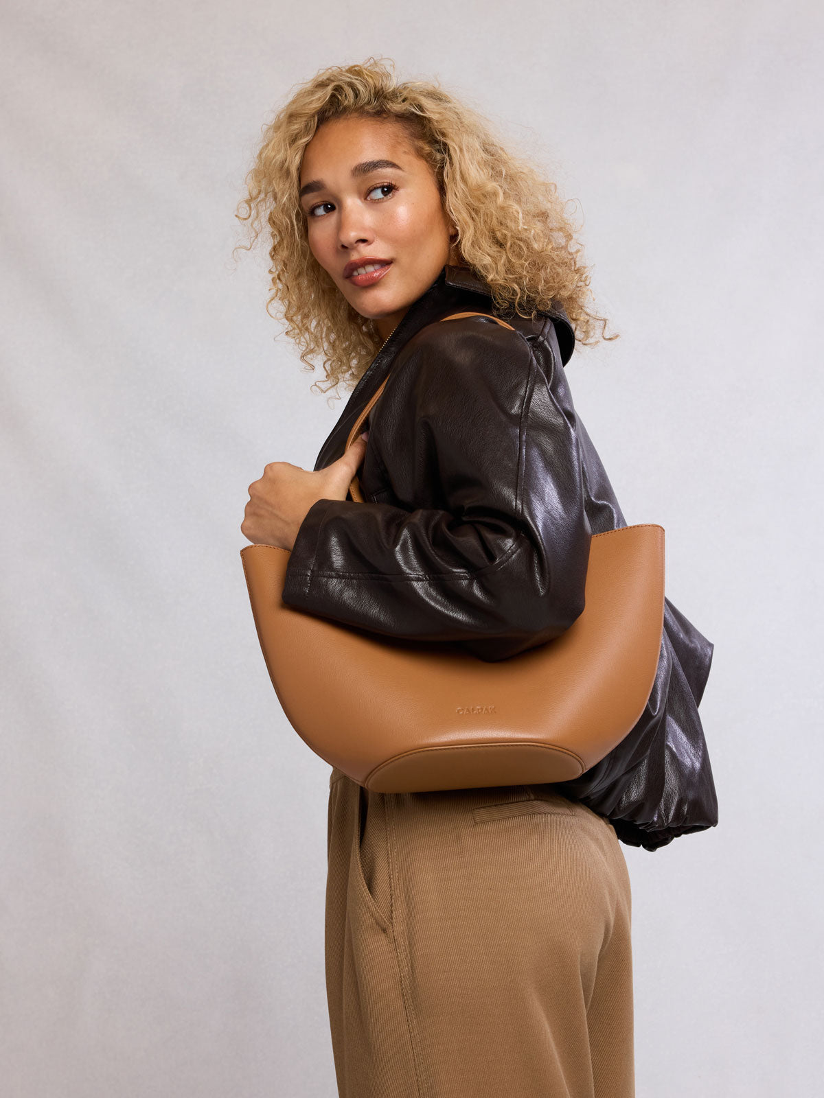 Woman holding CALPAK Haven Tulip Tote in light brown Toffee; AHP2601-TOFFEE