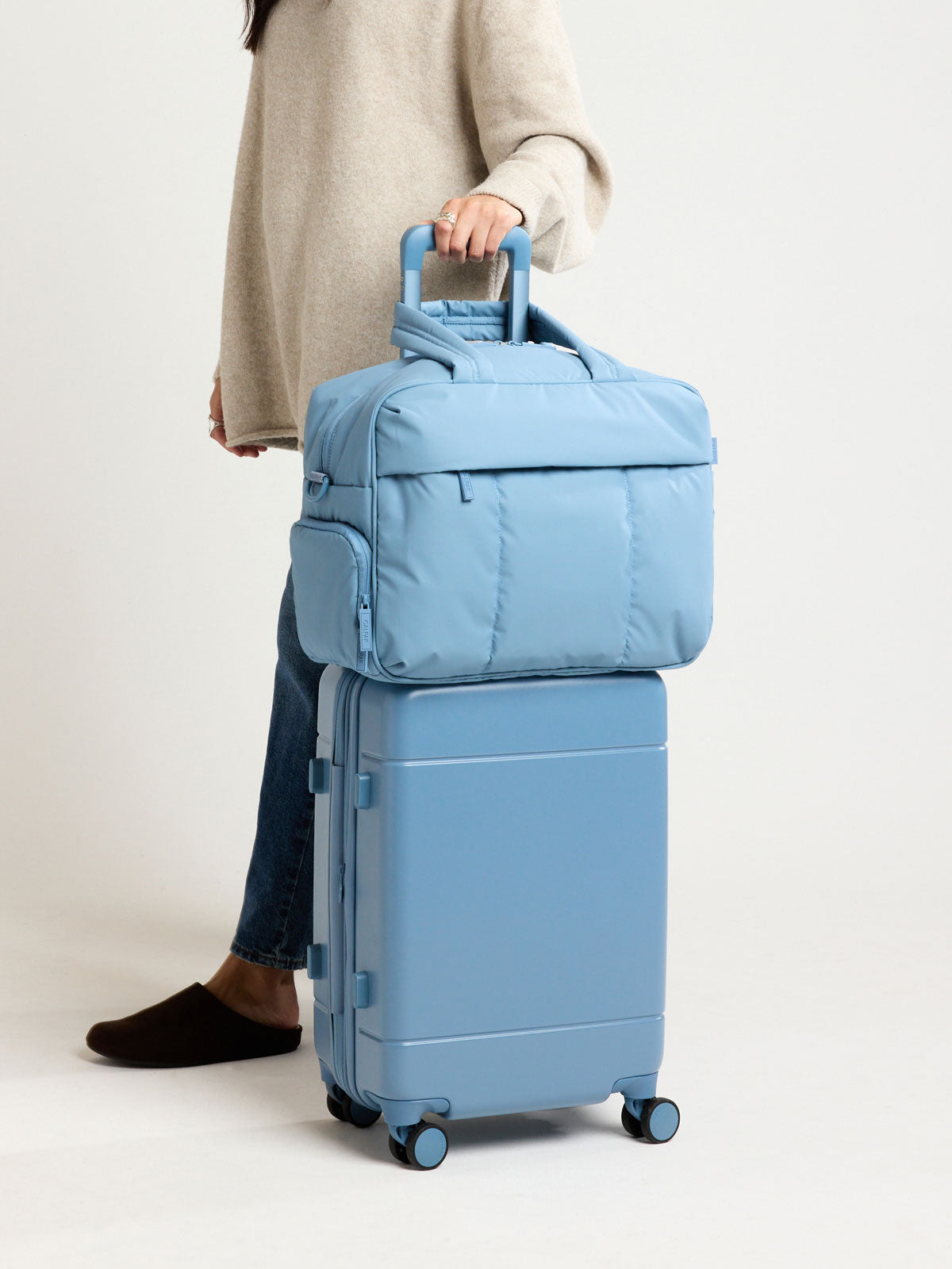 Model with CALPAK Hue Carry On Luggage in light blue French Blue ; LHU1020-NP-FRENCH-BLUE