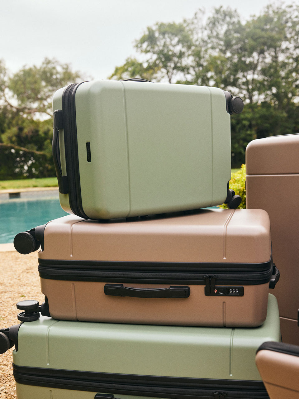 CALPAK Hue Carry On Luggage in green Juniper stacked with other Hue Luggage ; LHU1020-NP-JUNIPER