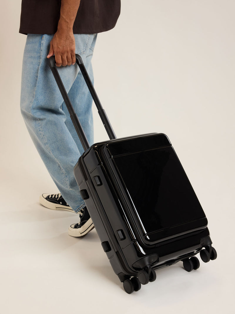 Model with CALPAK Hue Front Pocket Carry On Luggage in Glazed Black