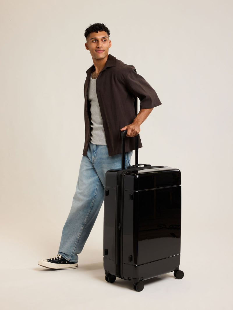Model with CALPAK black Hue Large Luggage in Glazed Black