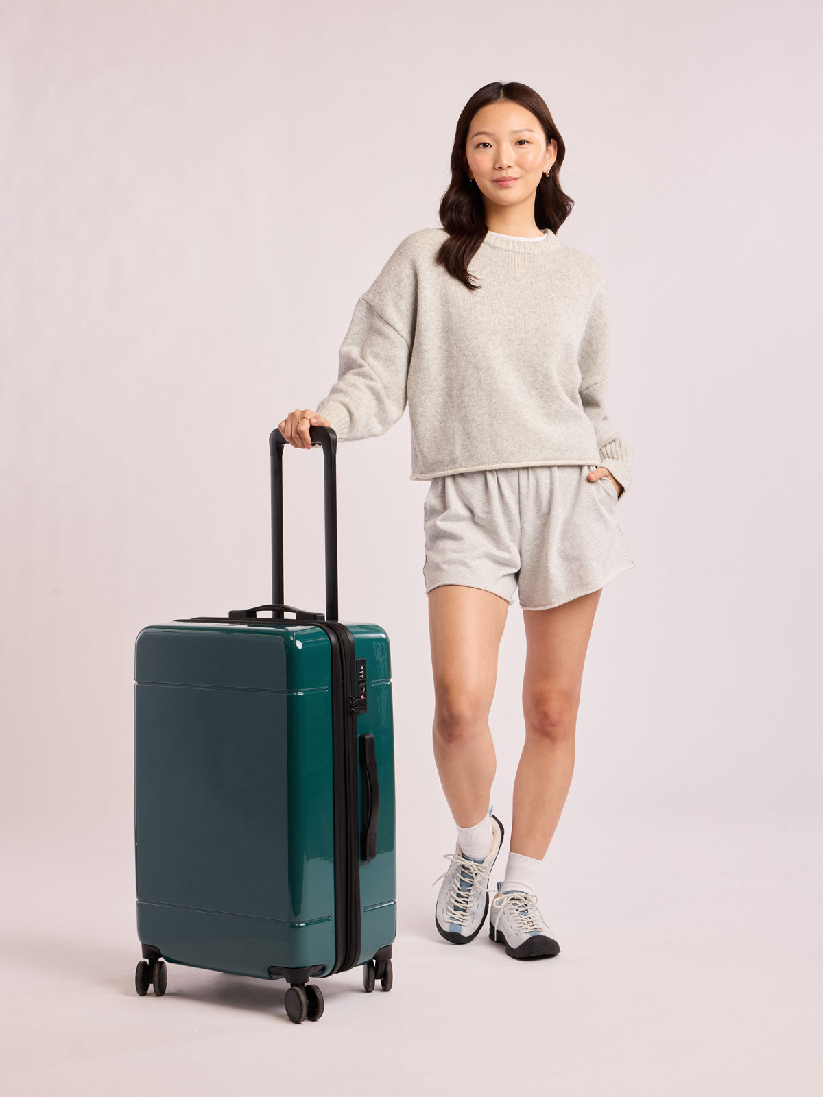 Woman wiht CALPAK Hue Medium Luggage in dark green Kale; LHU1024-GLAZED-KALE
