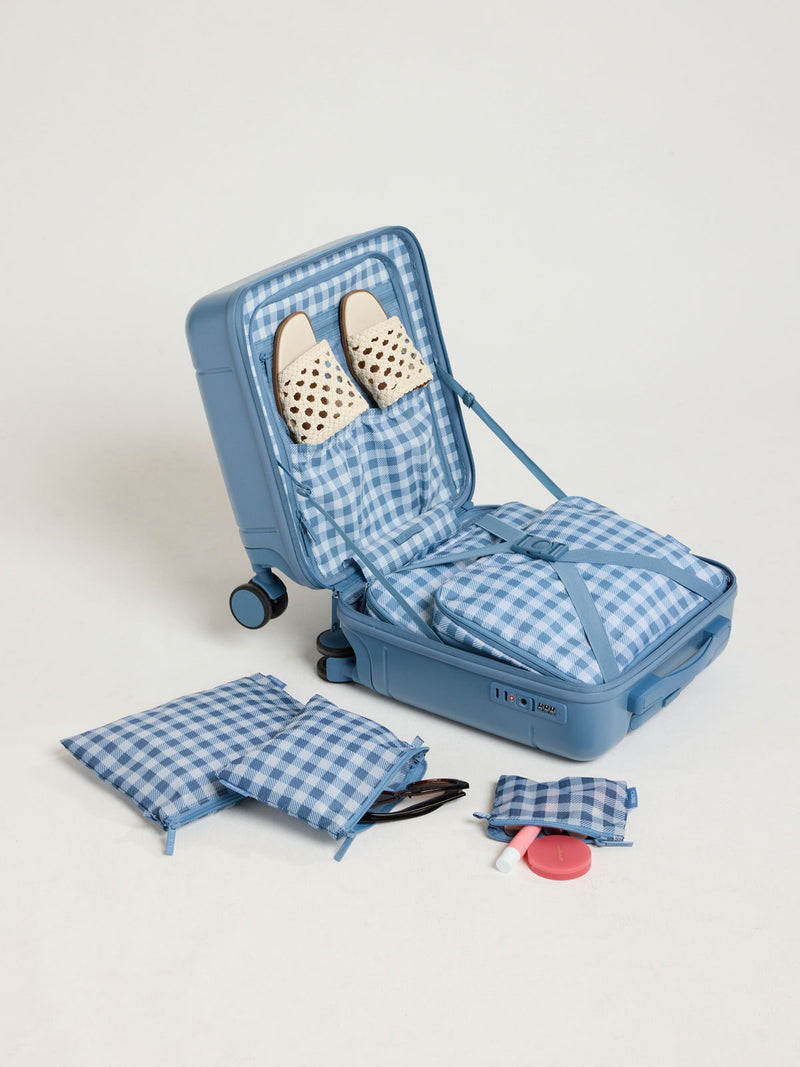 Opened view with items in the CALPAK Hue Mini Carry On in light blue French Blue with Gingham interior