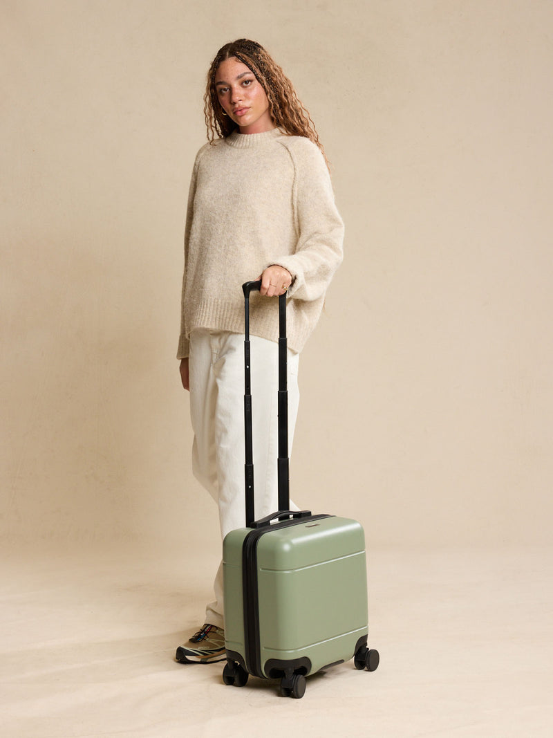 Model with CALPAK Hue Mini Carry On Luggage in green Juniper
