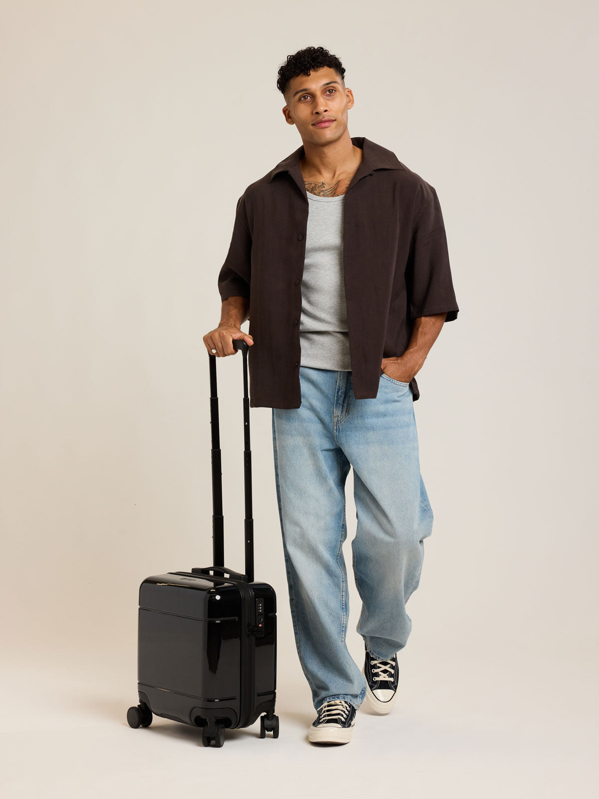 Model with CALPAK Glazed Black Hue Mini Carry On suitcase with a black handle on a white background; LHU1014-GLAZED-BLACK