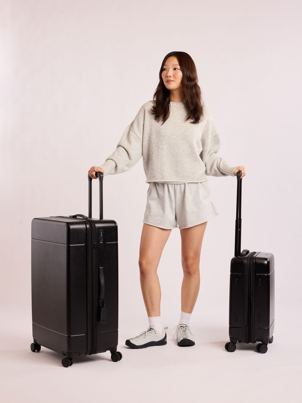Person holding two black luggage as part of Hue Starter Bundle against a white background; LHU8000-BLACK