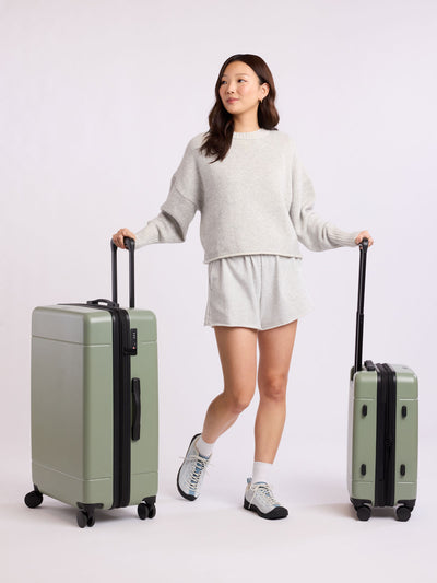 CALPAK Hue Starter Bundle in green Juniper that comes with Large and Carry On Luggage, Luggage Tag, Two Black Pouches, and Three Black Packing Cubes shown on a white background; LHU8000-JUNIPER view 2