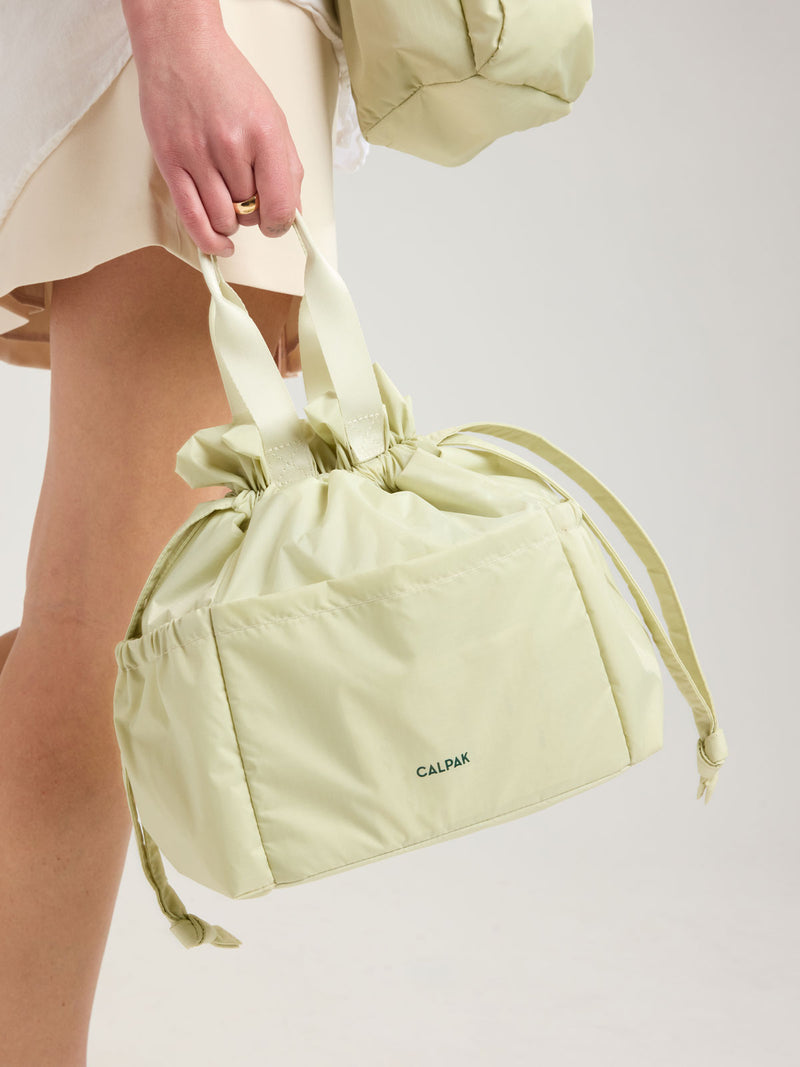 Person holding CALPAK Insulated Lunch bag in light green Celadon