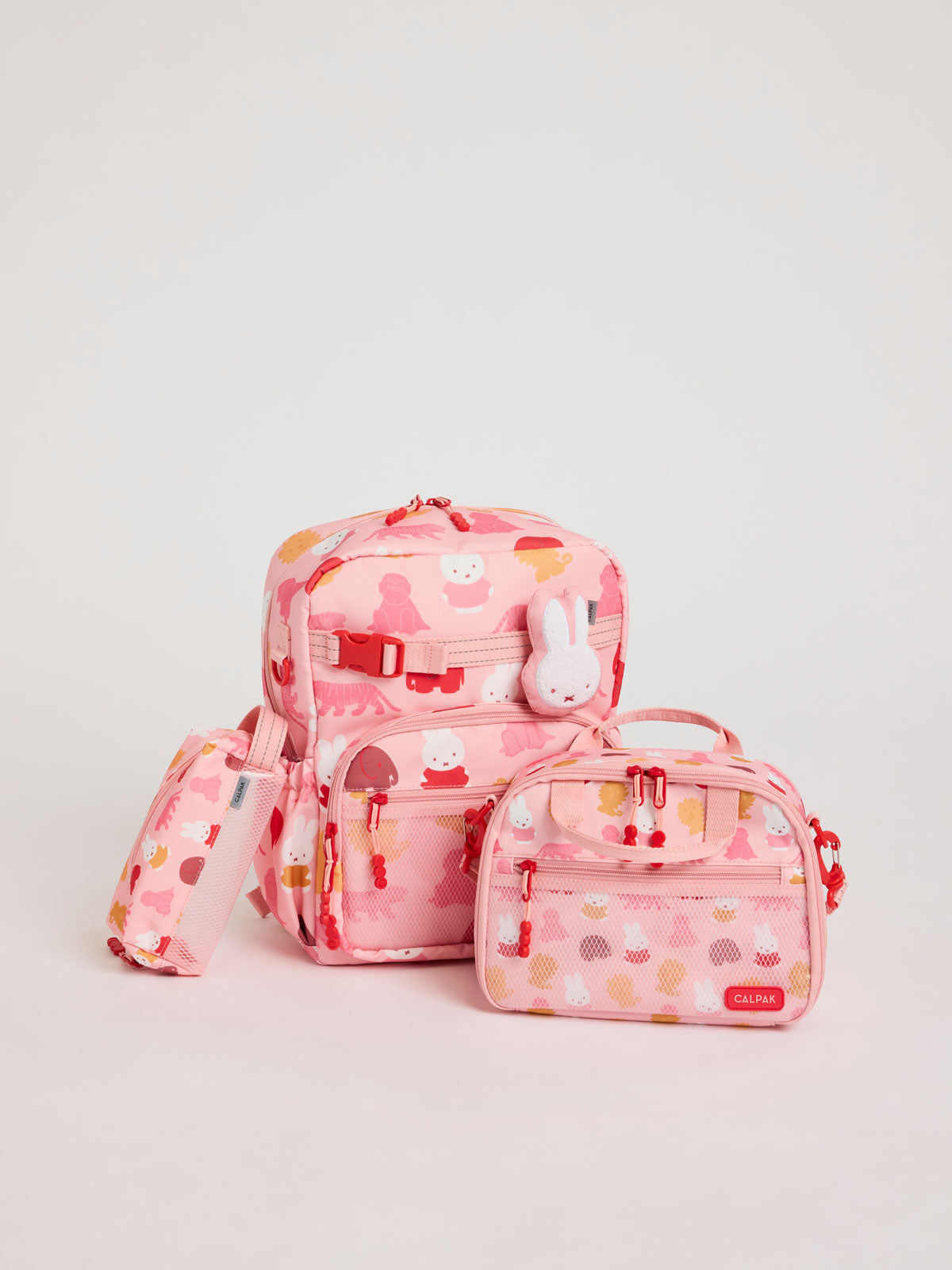 Colorful CALPAK + Miffy Kids Essentials Set with children's Medium backpack, lunch bag , pencil case set on a white background with pink accents and Miffy with other animals; BCKM5000-MIFFY-PINK-ZOO-TRIP
