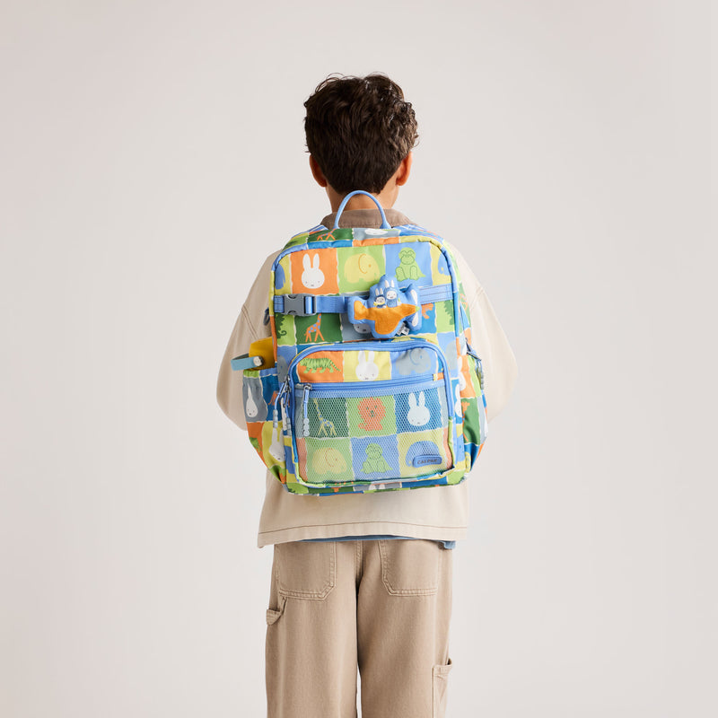 Child wearing the CALPAK + Miffy Large Backpack in Miffy Blue Zoo Trip featuring Miffy and other animal characters with colorful tiles