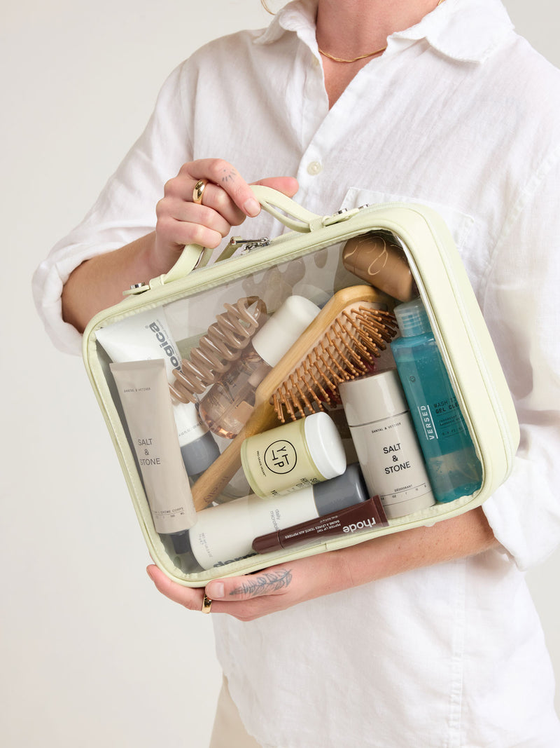 Person holding CALPAK Large Clear Cosmetic Case in light green Celadon