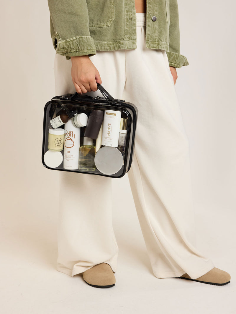 Person holding CALPAK Large Clear Cosmetics Case in black Glazed Black