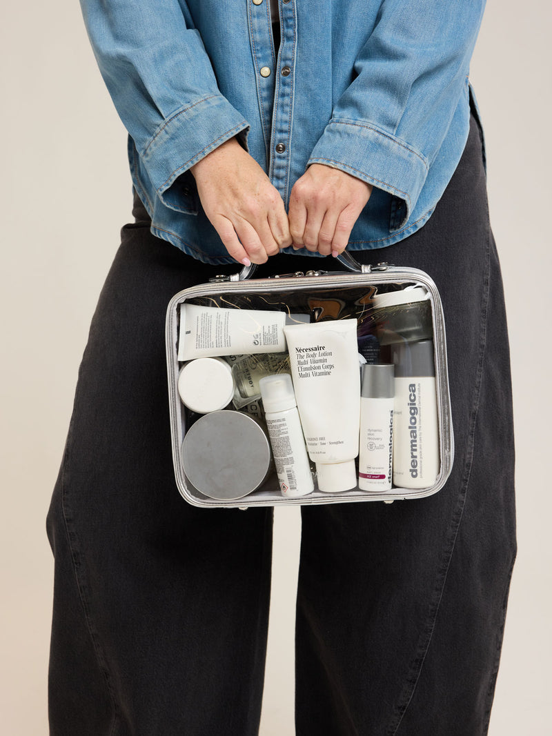 Model holding CALPAK Large Clear Cosmetics Case in Silver