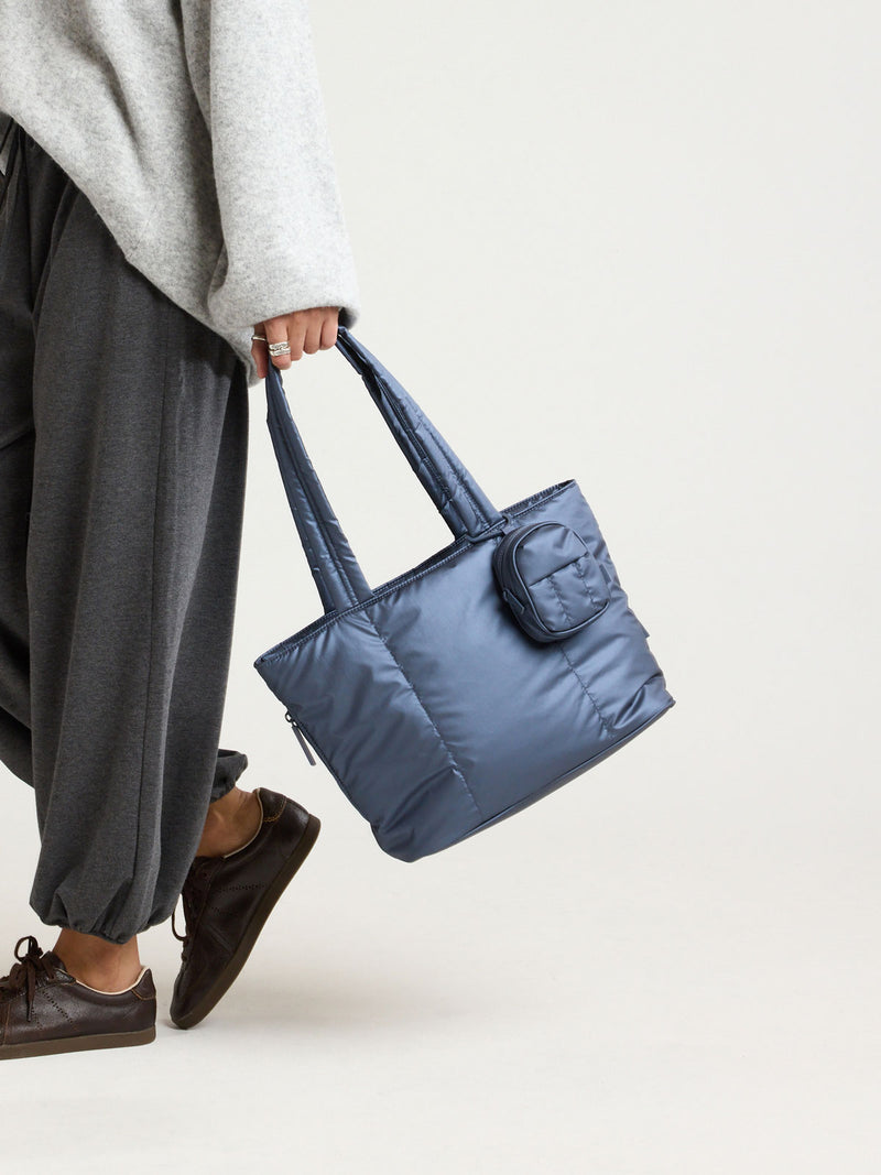 Model carrying a bag with the CALPAK Luka Backpack Zip Bag Charm in metallic dark blue Metallic Indigo clipped