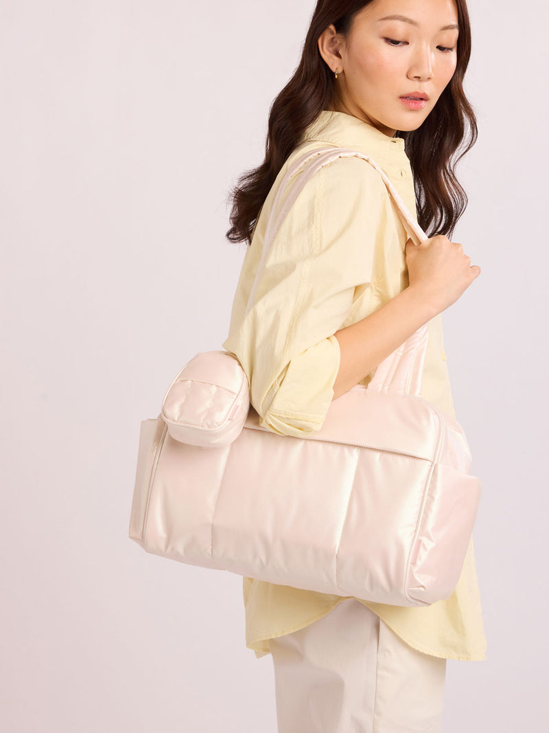 Woman wearing bag with CALPAK Luka Backpack Zip Bag Charm in light pink Pearlescent