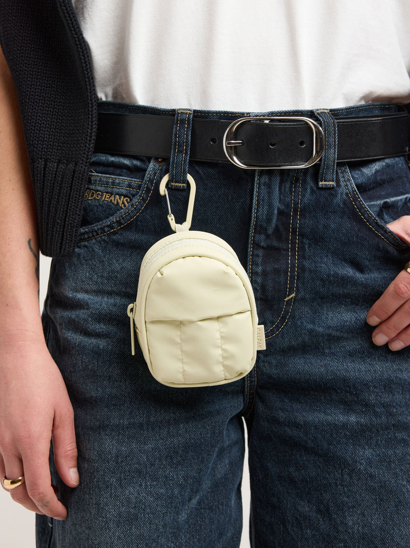 Person with CALPAK Luka Backpack Zip Bag Charm in light green Celadon